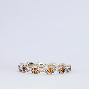 May include: A silver band ring with a row of small, oval-shaped orange gemstones set in a delicate, scalloped design.