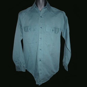 May include: A long-sleeved, dark green button-down shirt with two large pockets on the chest.