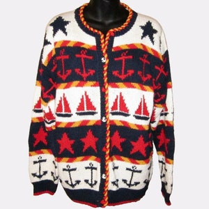 May include: A blue, white, red, and yellow knitted cardigan with a nautical theme. The cardigan features red sailboats, white anchors, and red stars on a blue background.