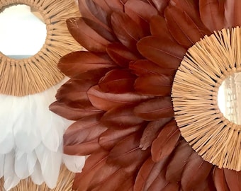 May include: Two round mirrors with a woven straw frame. One mirror is surrounded by brown feathers and the other is surrounded by white feathers.