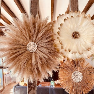 Puede incluir: Tres decoraciones murales circulares. Una está hecha de hierba de la pampa beige con un centro de concha. Otra está hecha de plumas blancas con un centro dorado. La tercera es de paja tejida con un centro de concha.