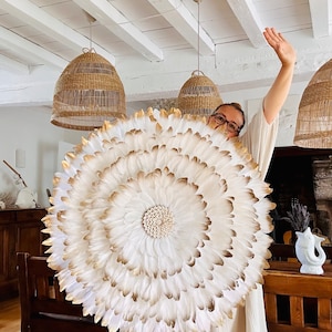 Jujuhat “Golden White” – handcrafted wall decoration made of white feathers, gold and natural cowries