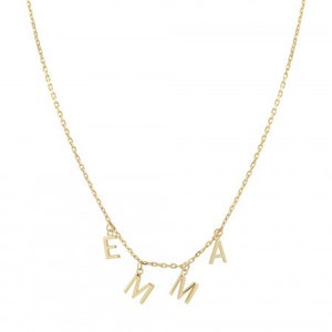 Puede incluir: Un collar dorado con el nombre "EMMA" deletreado con colgantes individuales de letras. La delicada cadena sostiene las letras, que están en una fuente simple, sin serifa. El collar se muestra sobre un fondo blanco.
