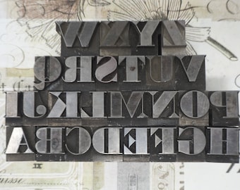 Könnte beinhalten: Ein Satz vintage Metall-Letterpress-Druckblöcke, alphabetisch geordnet, mit den Buchstaben W, X, Y, Z, Q, R, S, T, U, V, I, J, K, L, M, N, O, P, A, B, C, D, E, F, G und H.