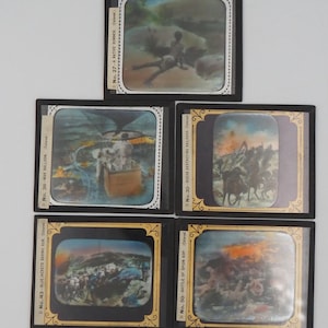 May include: A collection of five antique glass slides, each framed in black. The slides depict various scenes, including a Native runner, a hot air balloon, a battle scene, and a group of soldiers. The slides are labeled with numbers and titles.