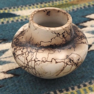 May include: A handcrafted, off-white ceramic vase with a rounded body and a wide opening. The vase features intricate black lightning-like patterns across its surface. The vase is approximately 4 inches in height and 5 inches in diameter.