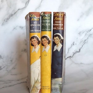 May include: Three vintage paperback books with yellow and black covers. The books are titled "Cherry Ames at Spencer", "Cherry Ames Clinic Nurse", and "Cherry Ames Night Supervisor". All three books are by Julie Tatham.