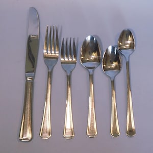 May include: A set of six silver-toned flatware pieces, including a knife, two forks, and three spoons.