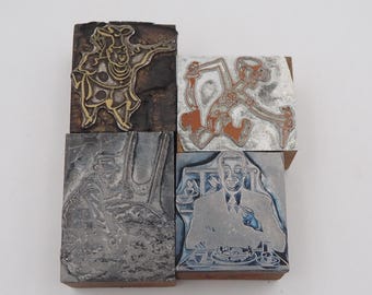 May include: Four vintage printing blocks with various designs. One block features a chef in gold and black. Another depicts a running figure in orange and gray. The other two blocks show a man and a person in a hat.