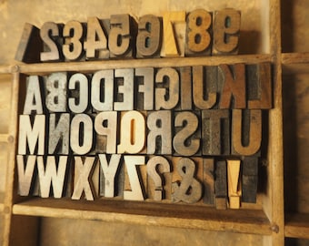May include: A wooden box filled with letterpress printing blocks. The blocks are made of wood and metal and feature the letters of the alphabet, numbers, and punctuation marks.