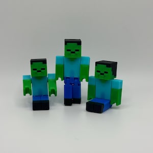 May include: Three green and blue Minecraft zombie figurines. The figures are standing and sitting.