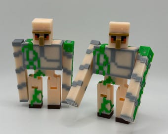 May include: Two 3D-printed figures of a Minecraft Iron Golem. The figures are beige with gray and green accents. The Iron Golems have blocky bodies, arms, and legs, with a rectangular head and a gold-colored face.