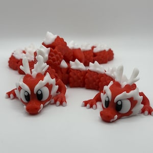 May include: Two red and white dragon figurines with cartoon-like faces. The dragons are curled up in a playful pose.