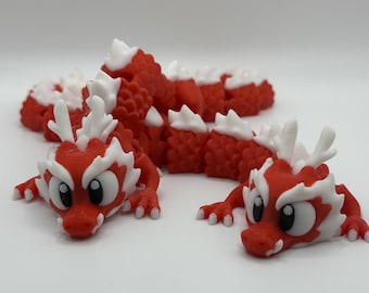May include: Two red and white dragon figurines with cartoon-like faces. The dragons are curled up in a playful pose.
