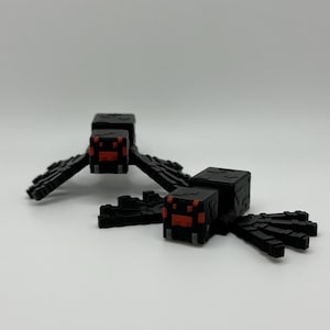 May include: Two black plastic Minecraft spider figurines with red eyes. The spiders are posed with their legs outstretched.