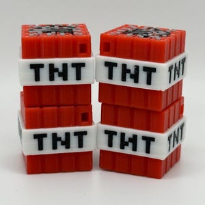 May include: Two stacks of red and white Minecraft TNT blocks. Each block has a black TNT label.