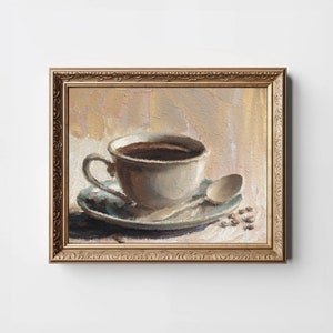 May include: A painting of a white coffee cup with a saucer and a spoon, filled with coffee. The cup is on a table with coffee beans scattered around it. The painting is framed in a gold frame.