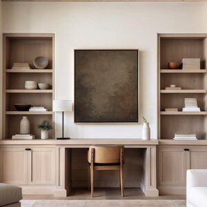 May include: A home office setup with built-in light wood shelving units flanking a desk. The desk has a wooden chair and a black lamp. A large abstract painting hangs above the desk, and decorative items are on the shelves.