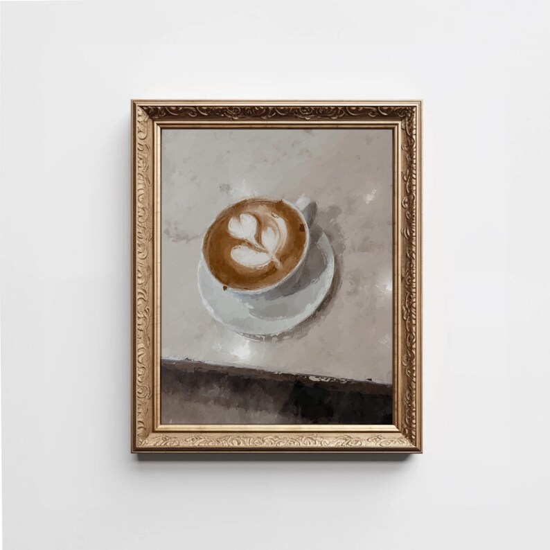 K&ouml;nnte beinhalten: Ein gerahmtes Gem&auml;lde einer Tasse Kaffee mit Latte-Art-Design. Der Kaffee befindet sich in einer wei&szlig;en Tasse und Untertasse auf einer hellbraunen Oberfl&auml;che. Der Rahmen ist golden mit verzierten Details.