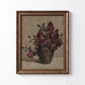 Könnte beinhalten: Ein gerahmter Kunstdruck mit einem Ölgemälde einer dunkelbraunen Vase, gefüllt mit tiefvioletten Fliederblüten. Das Kunstwerk hat einen strukturierten, beigen Hintergrund und befindet sich in einem dekorativen, dunkelbraunen Holzrahmen.