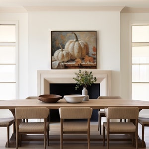 Pode incluir: Uma mesa de jantar de madeira com seis cadeiras, uma tigela de madeira, uma tigela branca e uma pintura de ab&oacute;boras brancas na parede acima de uma lareira.