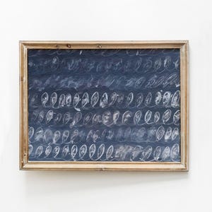May include: A framed abstract artwork featuring a dark blue background with white, swirling, calligraphic-style marks. The wooden frame has a natural, light brown finish. The artwork is a unique piece of wall decor.