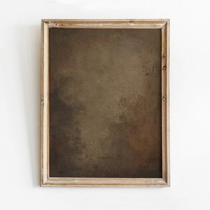 May include: A framed abstract art print with a neutral color palette. The artwork features a blend of brown and tan hues, creating a textured, painterly effect. The wooden frame adds a rustic touch to the piece.