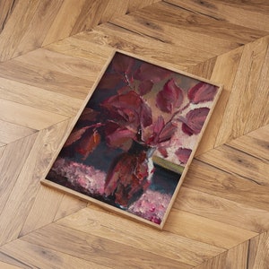 May include: A framed painting of a still life featuring a vase filled with deep red leaves. The vase is sitting on a pink and white patterned surface. The painting is framed in a simple wooden frame.