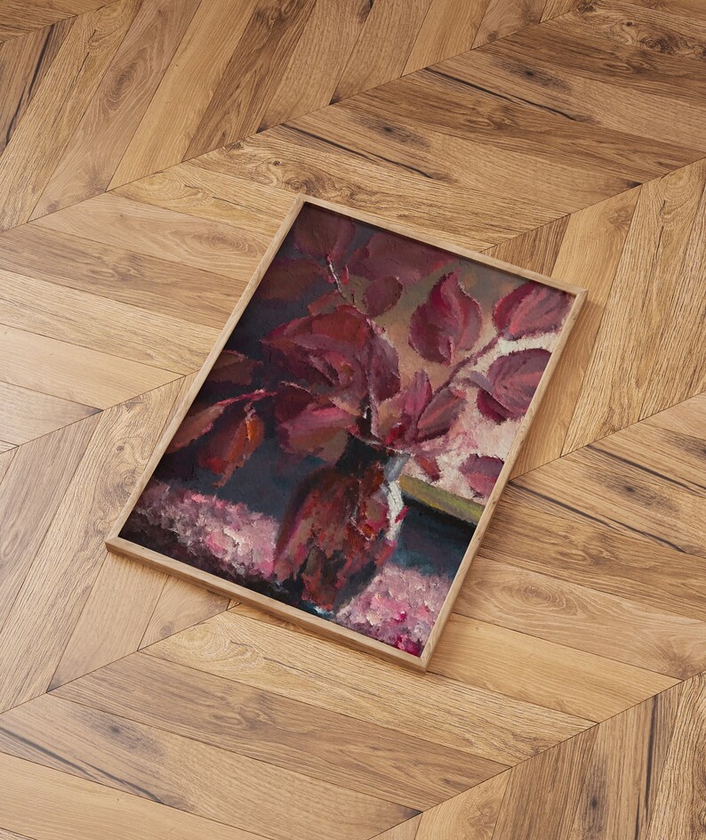 May include: A framed painting of a still life featuring a vase filled with deep red leaves. The vase is sitting on a pink and white patterned surface. The painting is framed in a simple wooden frame.