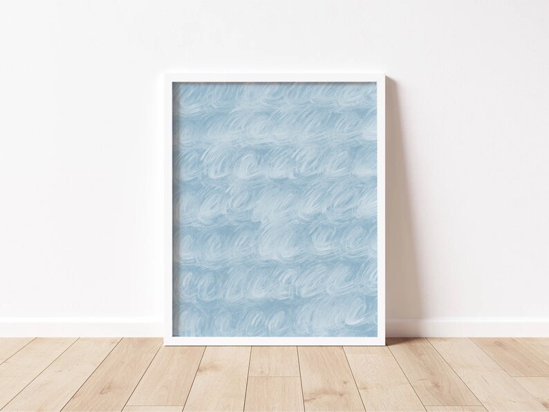 May include: A white framed print with a blue abstract design. The design features a repeating pattern of light blue brushstrokes.