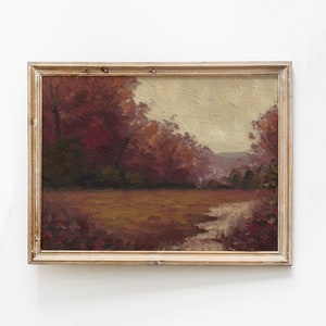 Può includere: Un dipinto incorniciato di un paesaggio con un ruscello che attraversa un campo di alberi. Gli alberi sono di un rosso intenso e il cielo è di un giallo chiaro. Il dipinto è in una cornice di legno semplice.