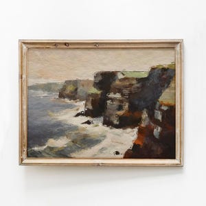 Może przedstawiać: Namalowany obraz w ramie przedstawiający morski krajobraz ze skalistymi klifami i rozbijającymi się falami. Obraz został wykonany w stonowanej palecie brązów, zieleni i błękitu.
