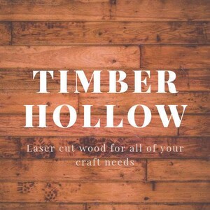 K&ouml;nnte beinhalten: Ein Holzhintergrund mit den Worten "TIMBER HOLLOW" in gro&szlig;en wei&szlig;en Buchstaben. Darunter steht in kleinerem Text "Lasergeschnittenes Holz f&uuml;r alle Ihre Bastelbed&uuml;rfnisse."