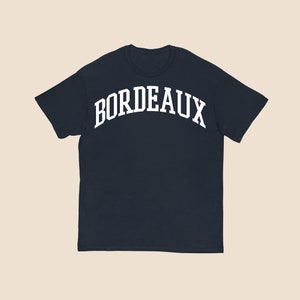 May include: A navy blue t-shirt with a white arch design that says "BORDEAUX".