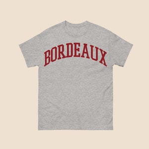 May include: A gray t-shirt with a red arched word "BORDEAUX" printed on the front.