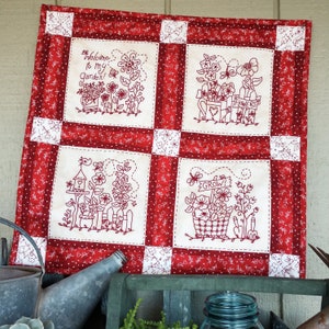 Peut inclure: Tissu matelassé rouge et blanc avec des motifs floraux brodés. Le tissu présente quatre carrés avec différents motifs floraux, dont un nichoir à oiseaux, un panier de fleurs et une pancarte qui dit "Grow!"