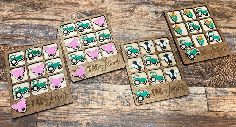 May include: Four wooden game boards with different farm animal and tractor images. Each board has a "Tag-Farm" label. The images include pigs, cows, tractors, and corn.