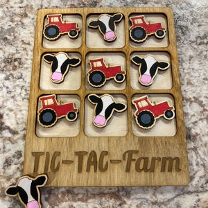 May include: A wooden tic-tac-toe game with a farm theme. The game board has nine squares, each with a picture of a red tractor or a black and white cow. The game is called "Tic-Tac-Farm".