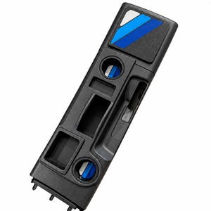 May include: A black automotive centre console insert featuring multiple storage compartments and two circular cup holders. The top section displays a decorative inlay with diagonal stripes in shades of blue, white, and black, adding a distinct visual accent.