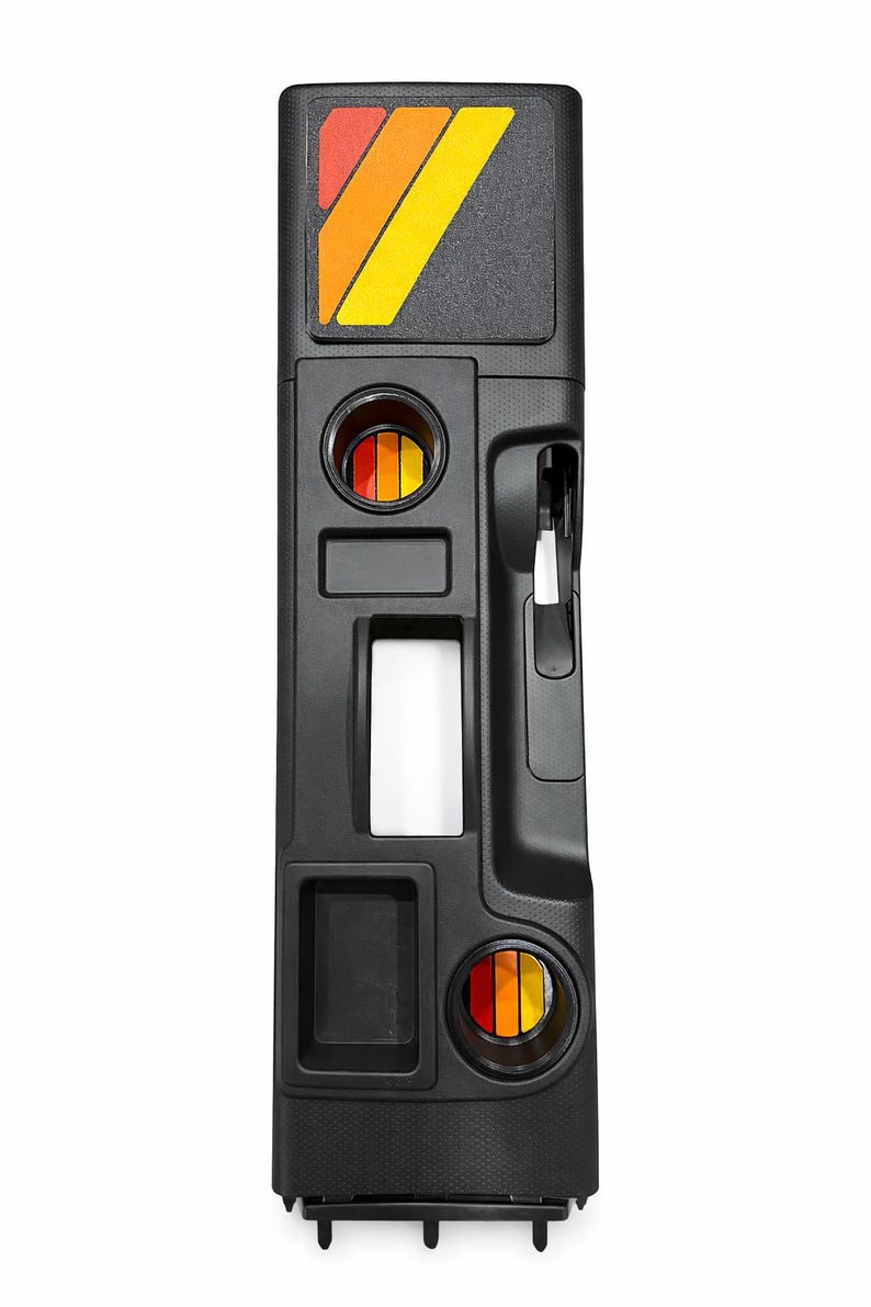 Pu&ograve; includere: Console automobilistica nera con superficie strutturata. Presenta un design retr&ograve; con una grafica a strisce rosse, arancioni e gialle. Include portabicchieri, una fessura rettangolare e una maniglia. La console &egrave; progettata per l'interno di un veicolo.