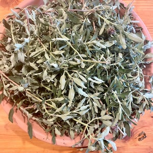 May include: A bowl filled with fresh green sage leaves and stems.
