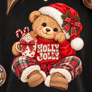 Puede incluir: Una camiseta negra con el gráfico de un oso de peluche marrón que lleva un gorro de Papá Noel rojo y un suéter rojo con el texto HOLLY JOLLY. El oso sostiene una taza con bastones de caramelo y una galleta, vistiendo pantalones de cuadros rojos y verdes.