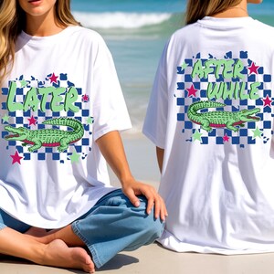 May include: White t-shirts with a graphic design featuring a green alligator, stars, and text. The front of the shirt says "LATER" and the back says "AFTER WHILE". The design is set against a blue and white checkered background.