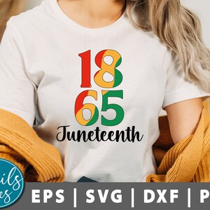 Può includere: T-shirt bianca con i numeri "1865" in rosso, giallo e verde, e la parola "Juneteenth" in corsivo nero. Un maglione color senape è drappeggiato sulle spalle. La parte inferiore dell'immagine mostra "Snails Tees" e icone di tipo di file.