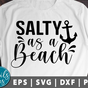 Puede incluir: Camiseta blanca con texto negro que dice "Salty as a Beach" con un gráfico de ancla.