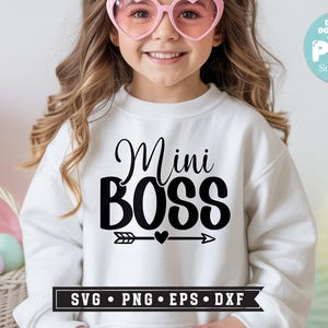 May include: White sweatshirt with the text "Mini BOSS" in black script and bold letters, with an arrow and heart design. The image includes a digital download badge and a basket with Easter eggs.