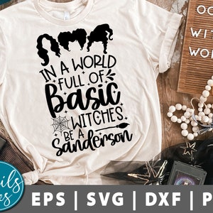 May include: A white t-shirt with a black graphic design that says "In a world full of basic witches be a Sanderson". The graphic also includes three witches with black hair and a spiderweb with a broom.