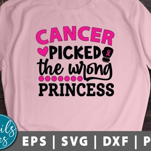 May include: Pink t-shirt with the text "Cancer Picked the Wrong Princess" in black. A pink heart and a pink boxing glove with a pink ribbon are included in the design.