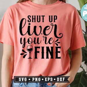 May include: A coral-colored t-shirt with the phrase "SHUT UP liver you're FINE" in black script and block letters, featuring a wine glass graphic. The shirt also has a "SVG PNG EPS DXF" graphic at the bottom.