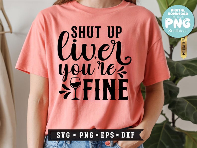 May include: A coral-colored t-shirt with the phrase "SHUT UP liver you're FINE" in black script and block letters, featuring a wine glass graphic. The shirt also has a "SVG PNG EPS DXF" graphic at the bottom.
